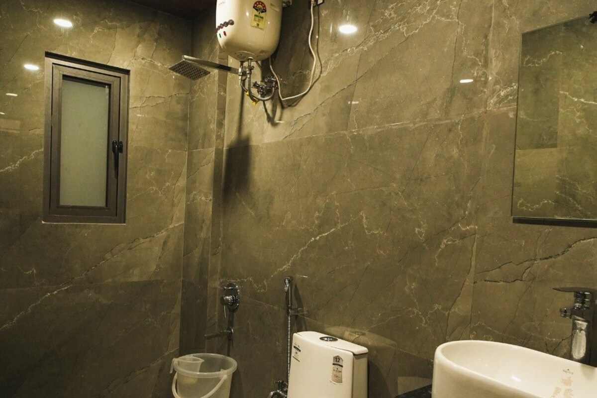 Un baño con inodoro, bidé y lavamanos, todo con paredes de mármol y techo de madera.