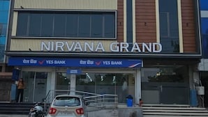 Un immeuble à plusieurs étages, avec une enseigne indiquant « JAKHAR TOWER HOTEL » et « NIRVANA GRAND » au rez-de-chaussée.