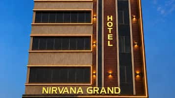 Hotellin julkisivu on moderni, sen yläpuolella on suuri, huomiota herättävä kyltti, jossa lukee »NIRVANA GRAND», ja sen sisäänkäynti on selkeästi näkyvissä, ja sen alla on pankin toimipiste.