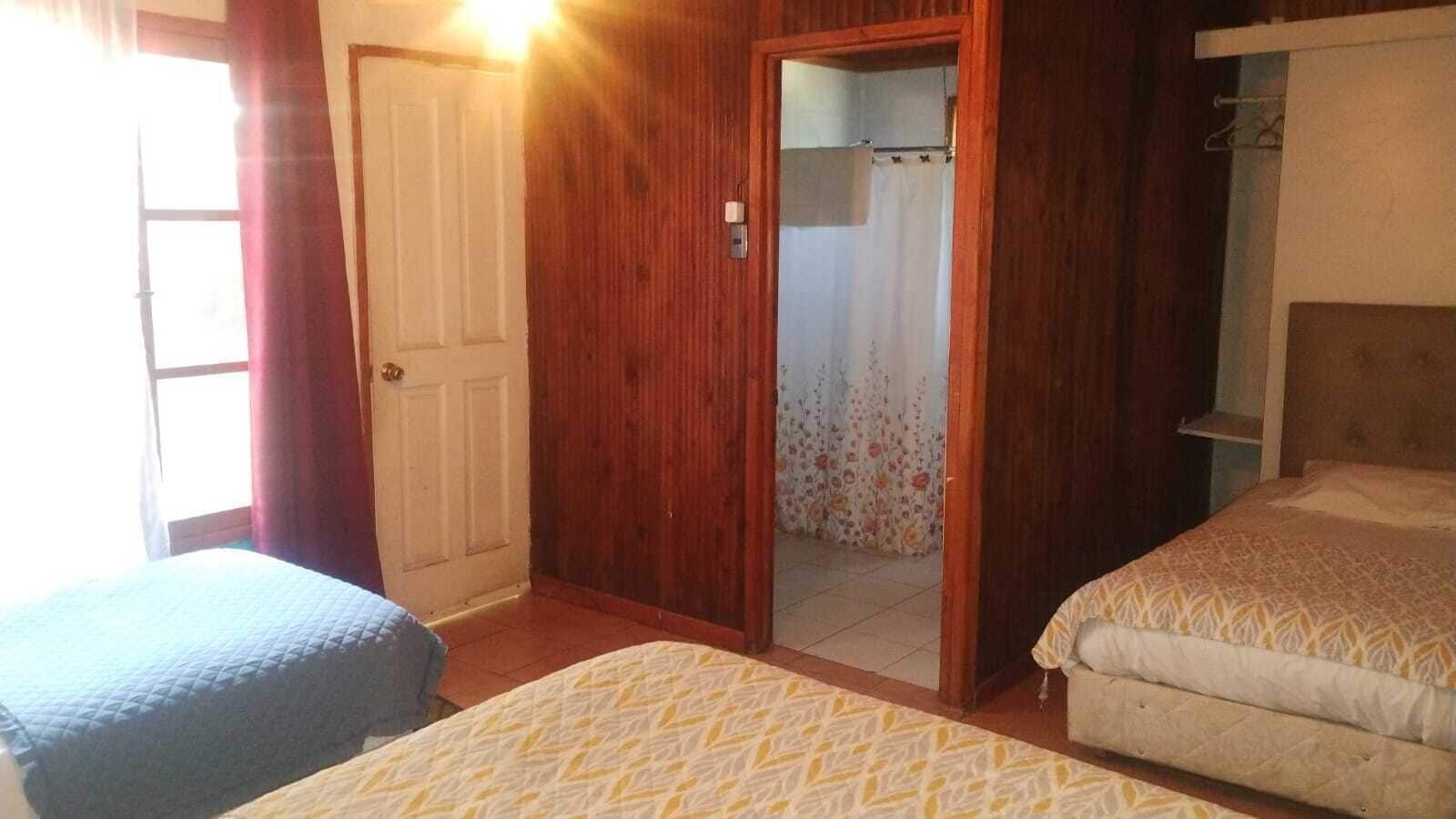 Habitación con dos camas, una puerta de madera y zona de ducha.