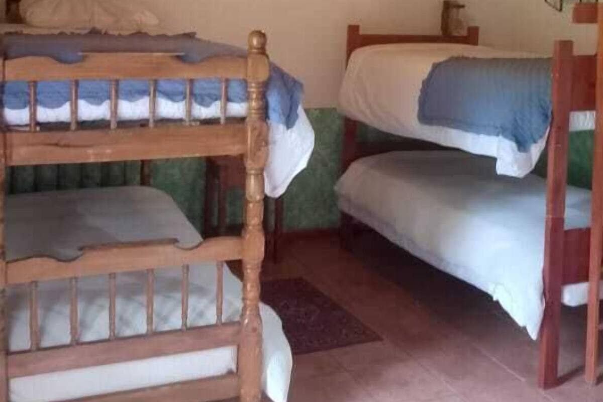 A room with two bunk beds, wooden ceiling, and a ceiling fan.