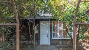 A rustic wooden building with a white door, a small window, and a wooden fence. - Lodge Los Naranjos de Mallarauco  (Melipilla)