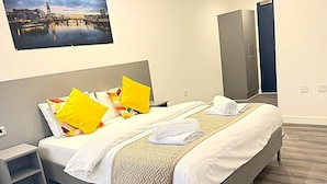 Habitación de hotel con cama, mesita de noche, armario y vistas a la ciudad.