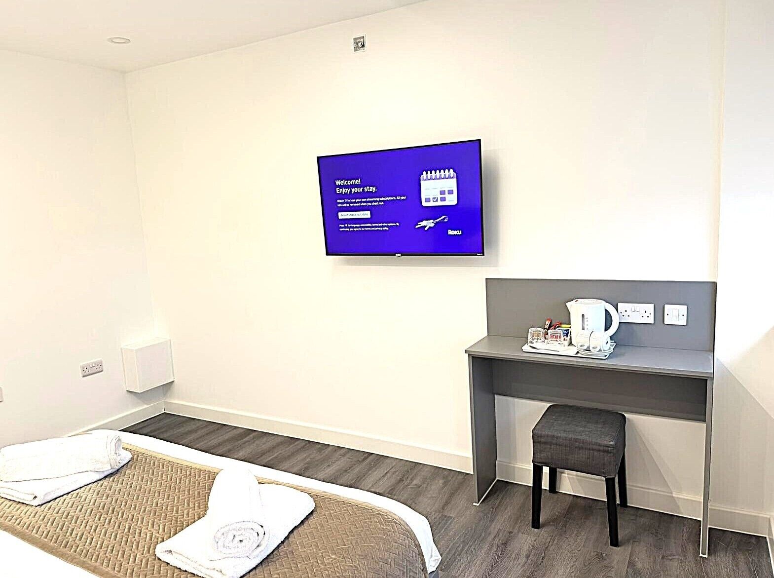 A hotel room with a bed, a desk, a television, and a coffee maker.