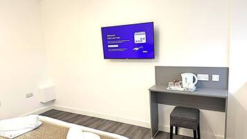A hotel room with a bed, a desk, a television, and a coffee maker.