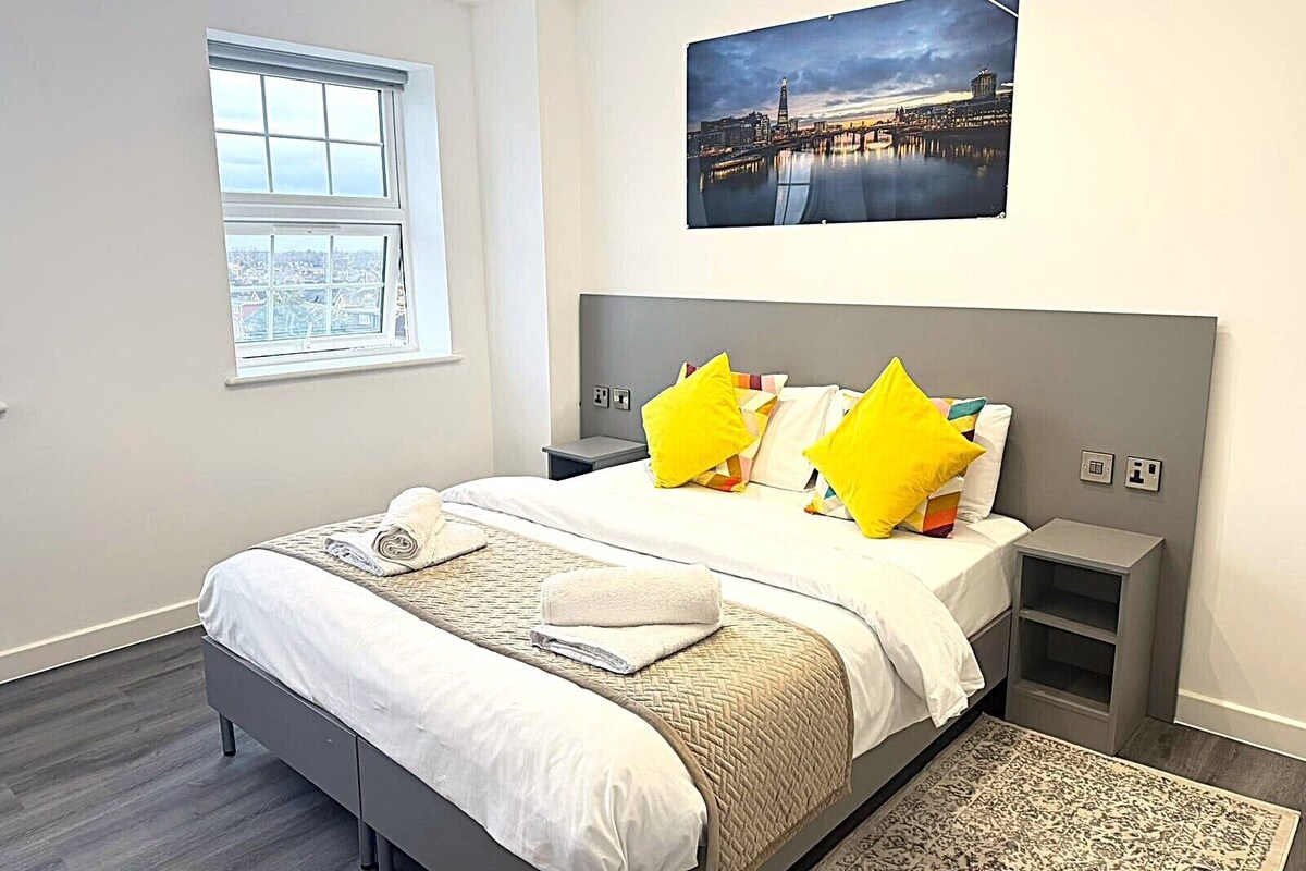 Ein modernes Hotelzimmer mit einem großen Bett, Blick auf die Stadt und einem Bild an der Wand.