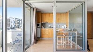 Eine moderne Küche mit Holzausstattung, einer Mikrowelle und einer Kaffeemaschine. Ein Glastisch mit Stühlen dient als Essbereich.