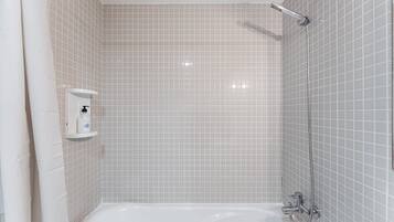 A bathroom with a bathtub, a shower, and a hand soap dispenser on the wall.