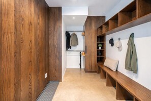 A hallway with wooden walls, a bench, and shelves with hats and jackets. - Mountain | Sauna | Camp de base du Massif (Saint-Philémon)