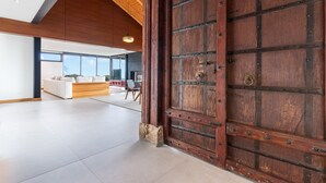Habitación amplia con una puerta de madera grande, un sofá moderno y vistas al exterior.