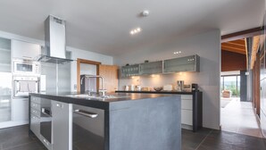 Una cocina moderna con una isla central, electrodomésticos integrados y vistas al exterior.