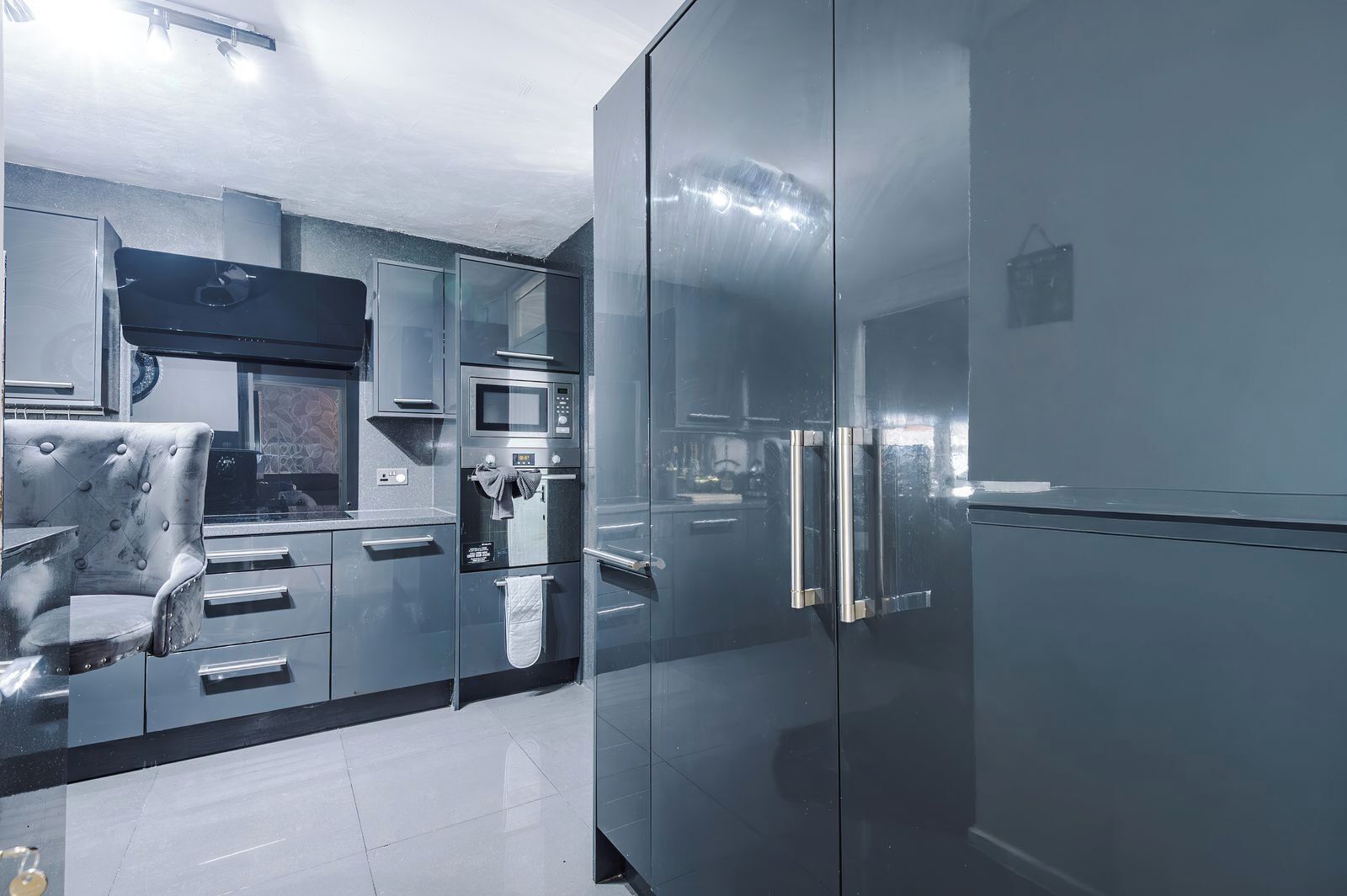 A modern kitchen with a built-in oven, microwave, and stainless steel refrigerator.