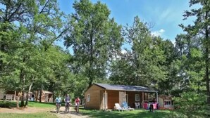 Un chalet rustique doté d’une véranda, entouré d’une forêt dense.