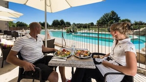 Two people dining at an outdoor table with a pool view. - ZEcamping 5 étoiles familial espace aquatique locatif TV BBQ 32m2 (Quimper)