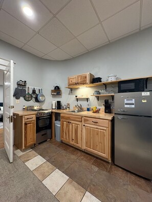 Una cocina con armarios de madera, un refrigerador de acero inoxidable y un microondas.