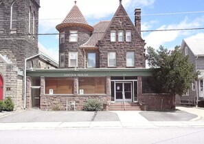 A historic building with a prominent tower, a large arched entrance, and a sign reading 'NOTTER HOUSE.' - NH5: Charming 1BR in Historic Home (DuBois)