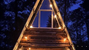 A wooden cabin with a triangular roof, a glass door entrance, and string lights. - Cabañas D Güereo By GEstores (Mineral del Chico)