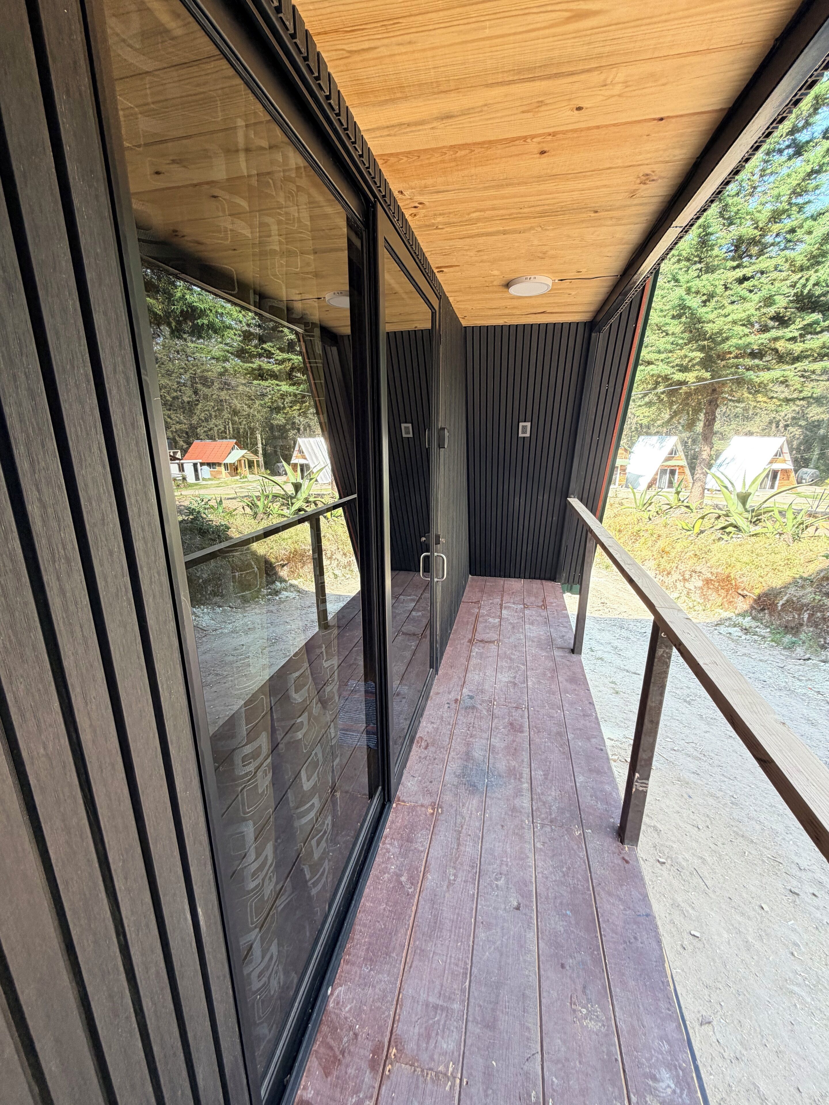 Una terraza de madera con puertas de cristal que dan a un balcón.