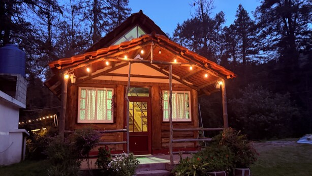 A rustic cabin with a wooden exterior, a porch with string lights, and potted plants around the entrance. - Cabañas D Güereo By GEstores (Mineral del Chico)