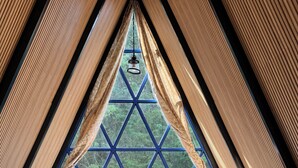 A triangular room with a bed, a window, and wooden walls. - Cabañas D Güereo By GEstores (Mineral del Chico)