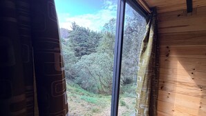 A room with a large window, wooden walls, and a view of a forested area. - Cabañas D Güereo By GEstores (Mineral del Chico)