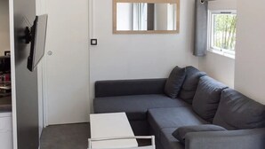 Un soggiorno moderno con un divano grigio, un tavolino da caffè bianco e una TV a schermo piatto montata a parete.