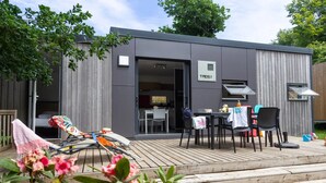 Un'area cucina esterna moderna con tavolo e sedie, un barbecue e un piccolo pontile.