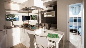 Eine moderne Küche mit weißen Schränken, einem Gasherd und einem Essbereich mit Tisch und Stühlen.