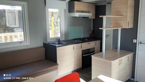 Una cucina compatta con piano cottura a gas, lavello e pensili in legno.