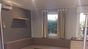 Un soggiorno moderno con un divano ad angolo integrato, un angolo cottura e una finestra con tende.