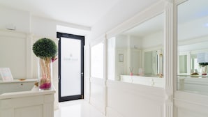 A hallway with a white door, a reception desk with a plant, and a large mirror reflecting the room. - Apartment in A Hotel 'Unit 1' with Wi-Fi (Gallipoli)