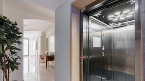 An elevator with a control panel, a potted plant, and a hallway with a wooden table and chairs. - Apartment in A Hotel 'Unit 1' with Wi-Fi (Gallipoli)