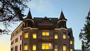 Un edificio de varios pisos con fachada simétrica, que presenta una entrada central con puertas dobles y un pequeño balcón superior.