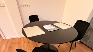 Ein runder Tisch mit vier schwarzen Stühlen, zwei Tischsets und einer Zeitschrift darauf.