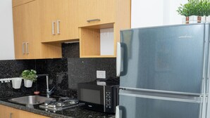 Una cocina moderna con armarios de madera, un refrigerador de acero inoxidable, un microondas y un fregadero.