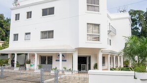Un edificio blanco con numerosas ventanas y un área de acceso cubierta.