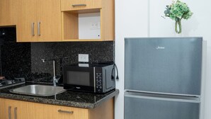 Una cocina con armarios de madera, un lavamanos de acero inoxidable, un microondas y un refrigerador de doble puerta.