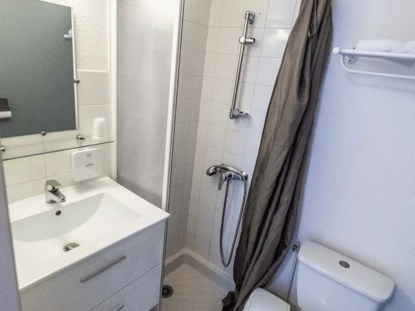 Ein Badezimmer mit weißem Waschbecken, Spiegel und Dusche.