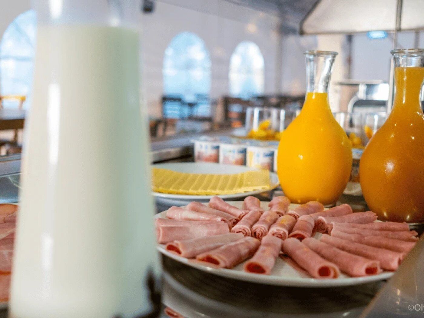 Un buffet de petit-déjeuner avec des charcuteries en tranches et du jus d’orange.