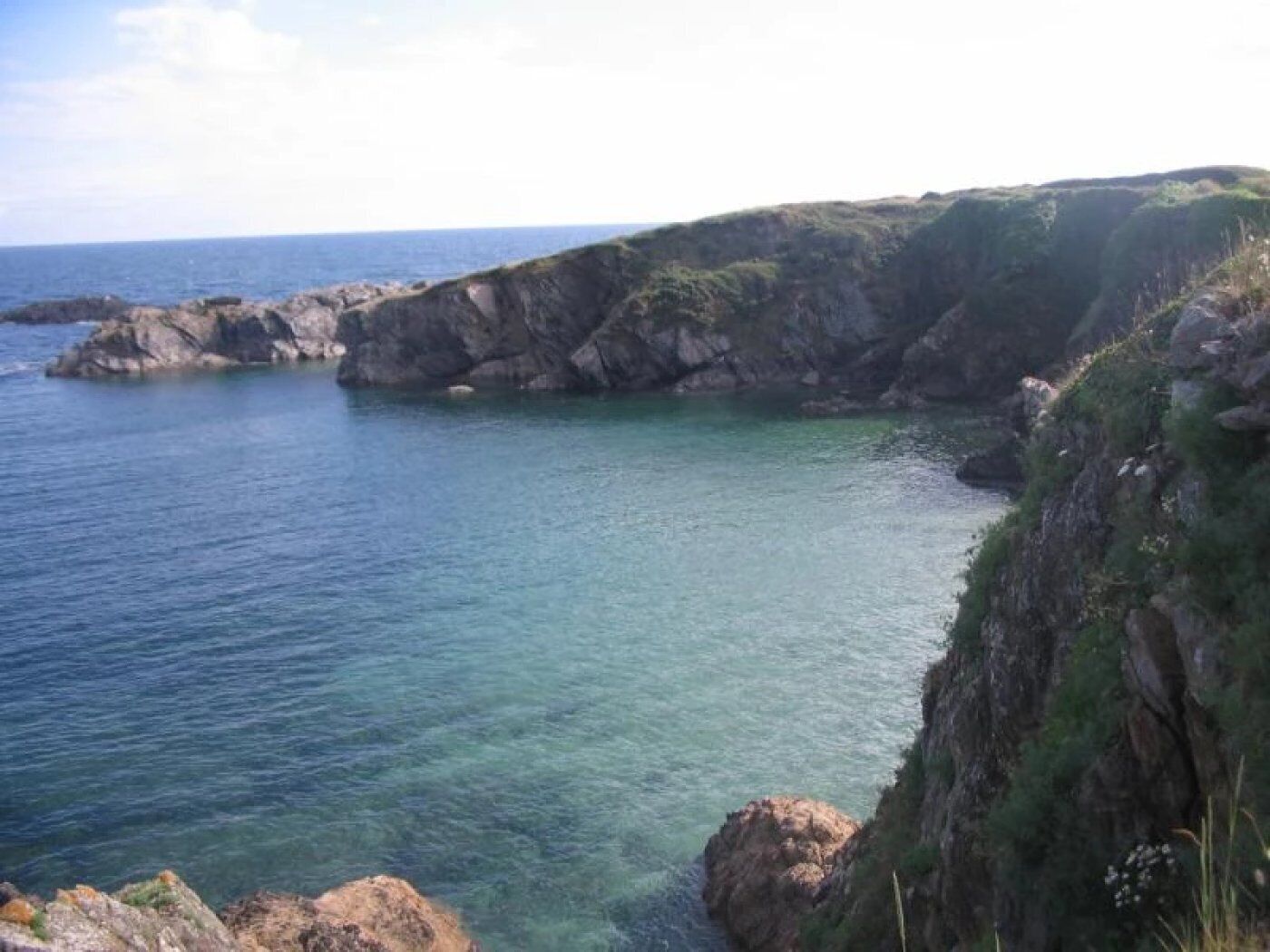 A coastal landscape with rocky cliffs and clear blue water.