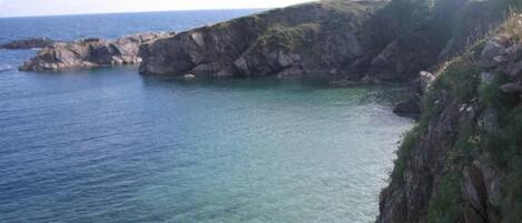 A coastal landscape with rocky cliffs and clear blue water.