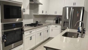 A modern kitchen with white cabinetry, stainless steel appliances, and a central island with a sink. - Desert Retreat - Relax and Enjoy (Las Cruces)