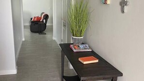 A hallway with a dark wooden table, a potted plant, and a few decorative items on the wall. - Desert Retreat - Relax and Enjoy (Las Cruces)