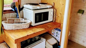 Uma cozinha compacta com micro-ondas, um refrigerador pequeno e bancada de madeira.