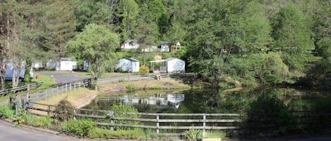 A lakeside property with cabins, a wooden fence, and a road.