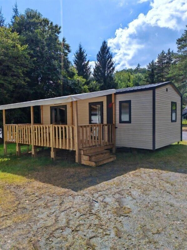 Une maison mobile de plain-pied avec une terrasse en bois et un petit porche.