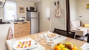 Une cuisine compacte équipée d’un four à micro-ondes, d’un réfrigérateur et d’un coin repas avec une table dressée pour deux personnes.