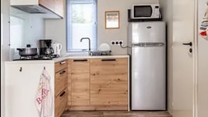 Une cuisine compacte avec des meubles en bois, un réfrigérateur en acier inoxydable, un four à micro-ondes et une cuisinière à gaz.