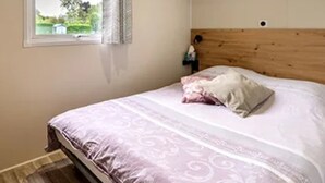 Une chambre à coucher avec un lit, une fenêtre avec des rideaux, une tête de lit en bois et une étagère au-dessus du lit.
