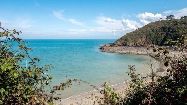 A coastal landscape with clear blue water, a sandy beach, and a hill with dense vegetation. - ZEcamping 3 étoiles mobil-home TV LV BBQ 27m2 4 pers (Pordic)